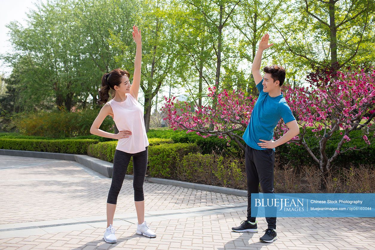 Happy young Chinese couple exercising in park