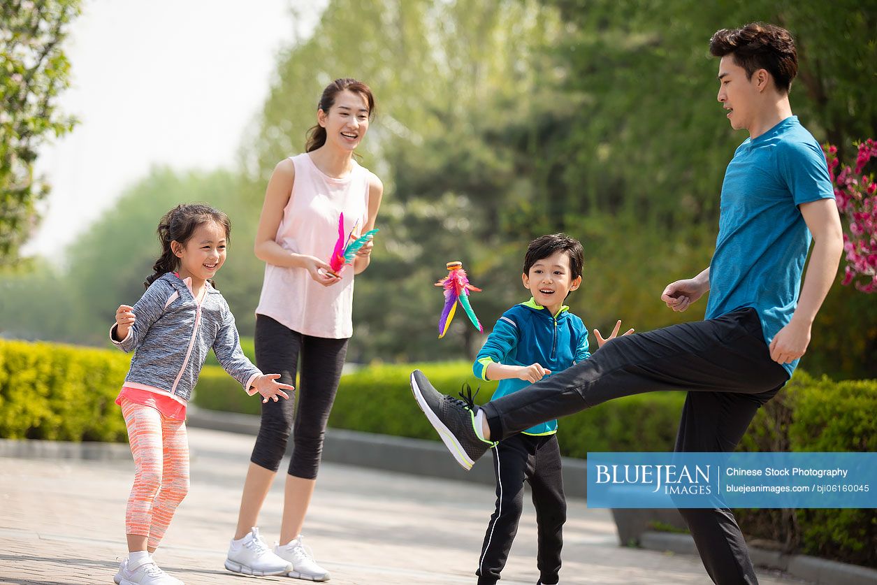 Happy young Chinese family kicking shutterlock in park