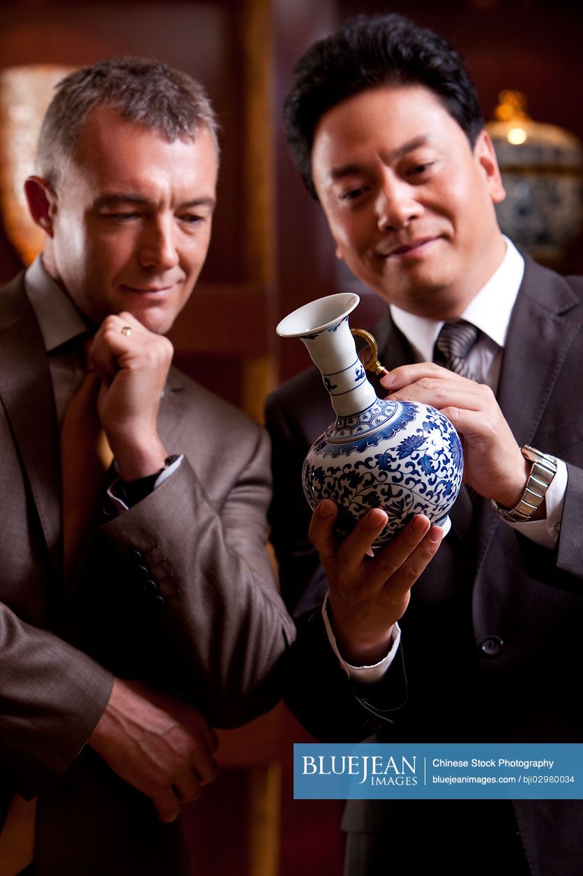 Mature Chinese businessmen admiring an antique Chinese vase