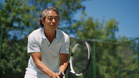 Happy Chinese man playing tennis ball