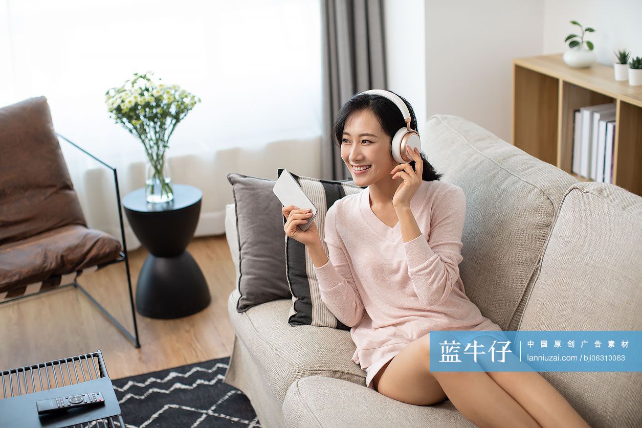 快乐年轻女士在家戴着耳机听音乐