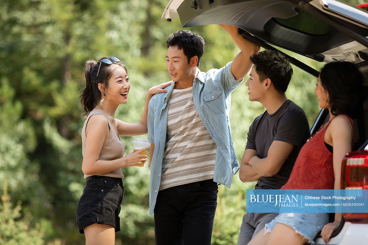 Happy young Chinese friends enjoying road trip