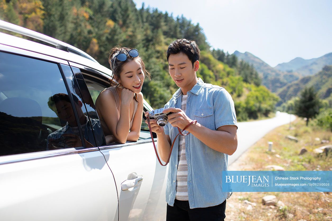 Happy young Chinese couple enjoying road trip