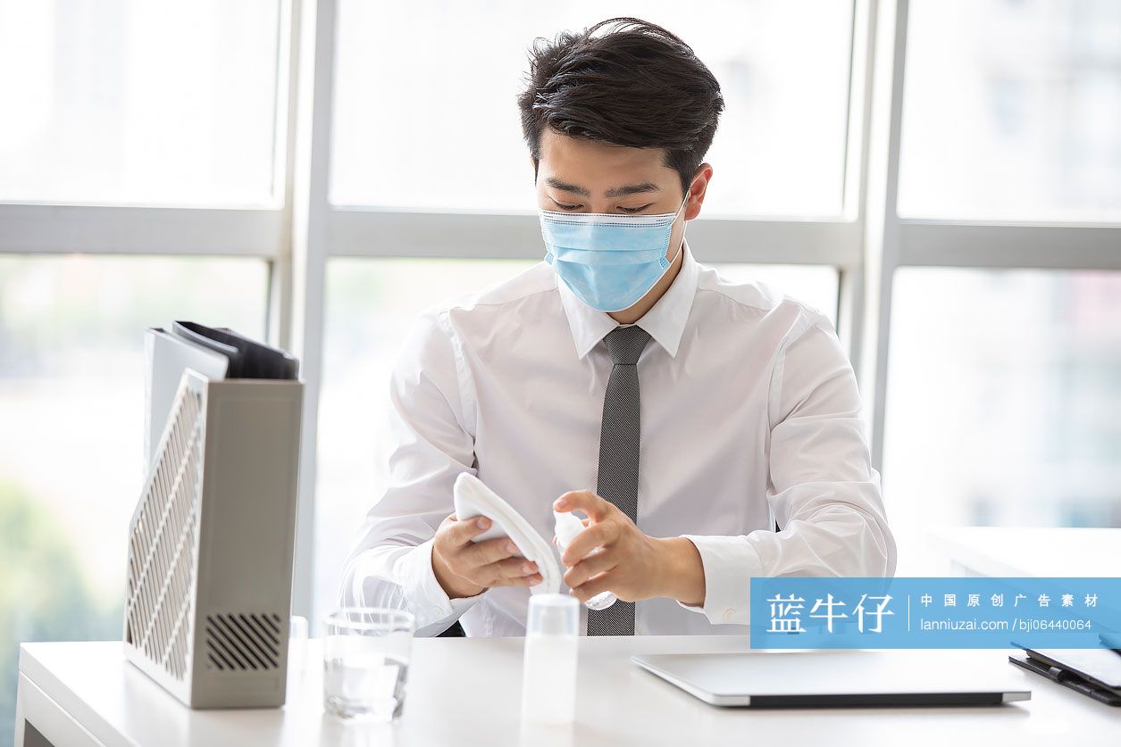 年轻的商务男士在办公室使用消毒液杀菌消毒