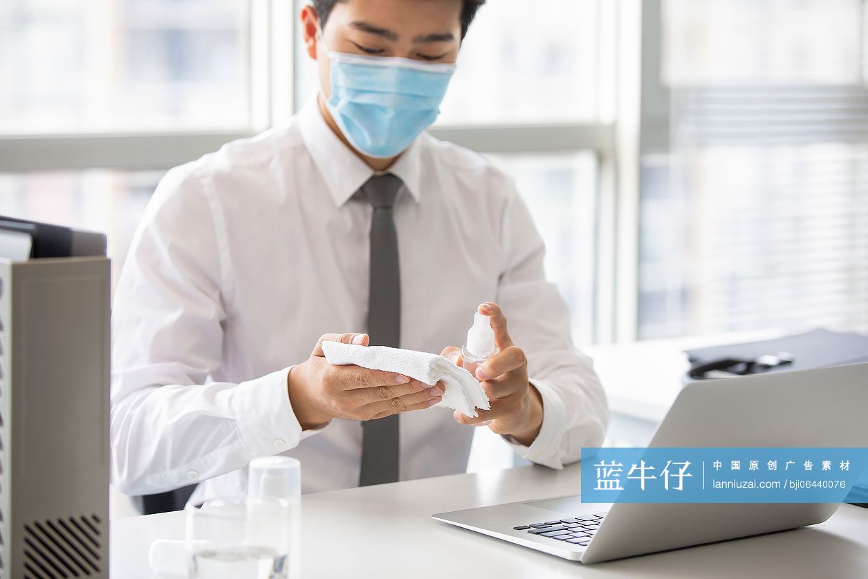 年轻的商务男士在办公室使用消毒液杀菌消毒