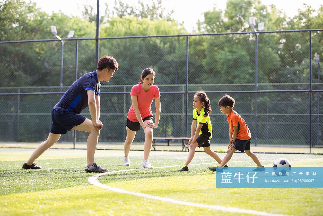 快乐的年轻家庭在足球场热身