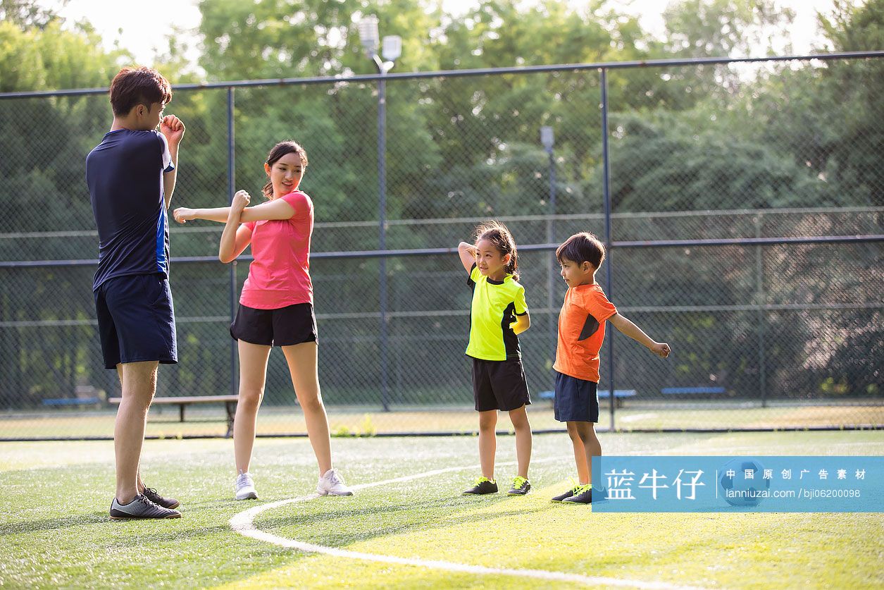 快乐的年轻家庭在足球场热身