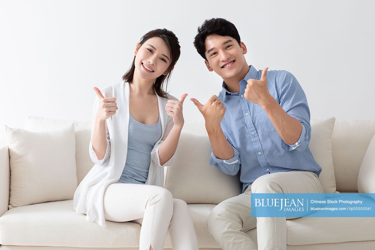 Cheerful young couple giving thumbs up