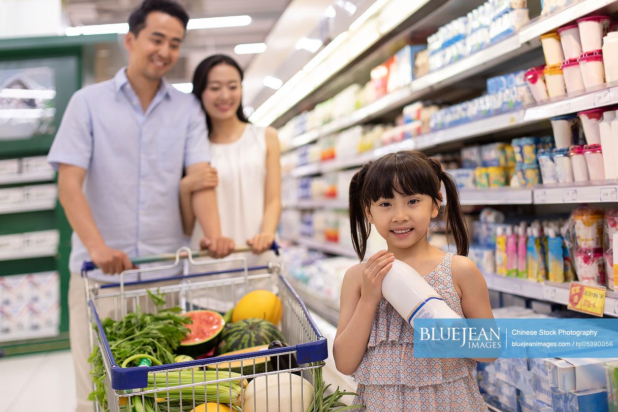 Happy young Chinese family shopping in supermarket