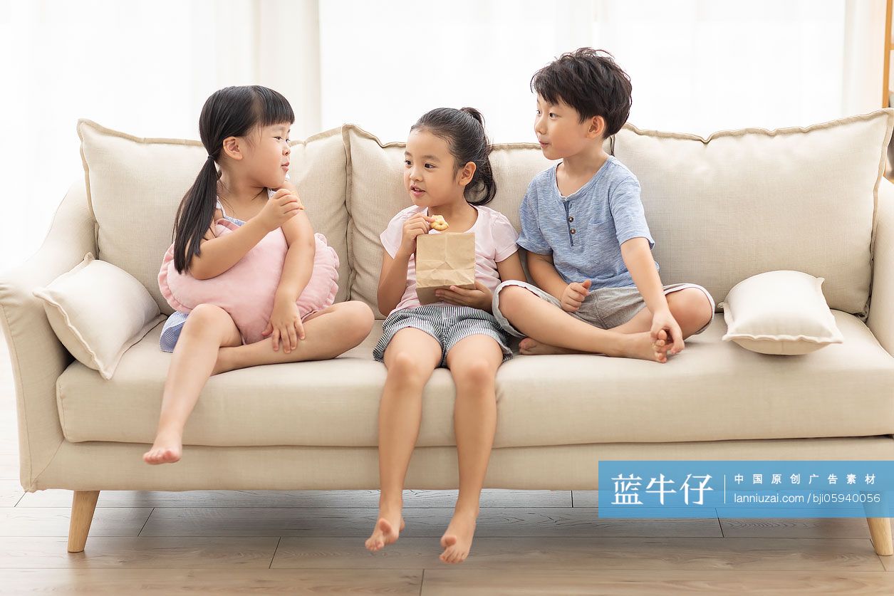 三个小朋友在沙发上吃饼干