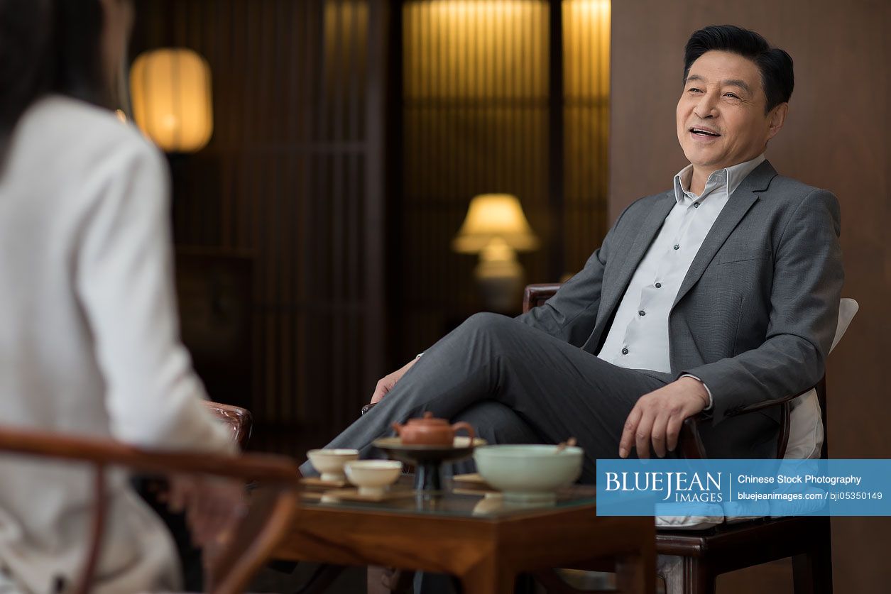 Cheerful Chinese businessman drinking tea