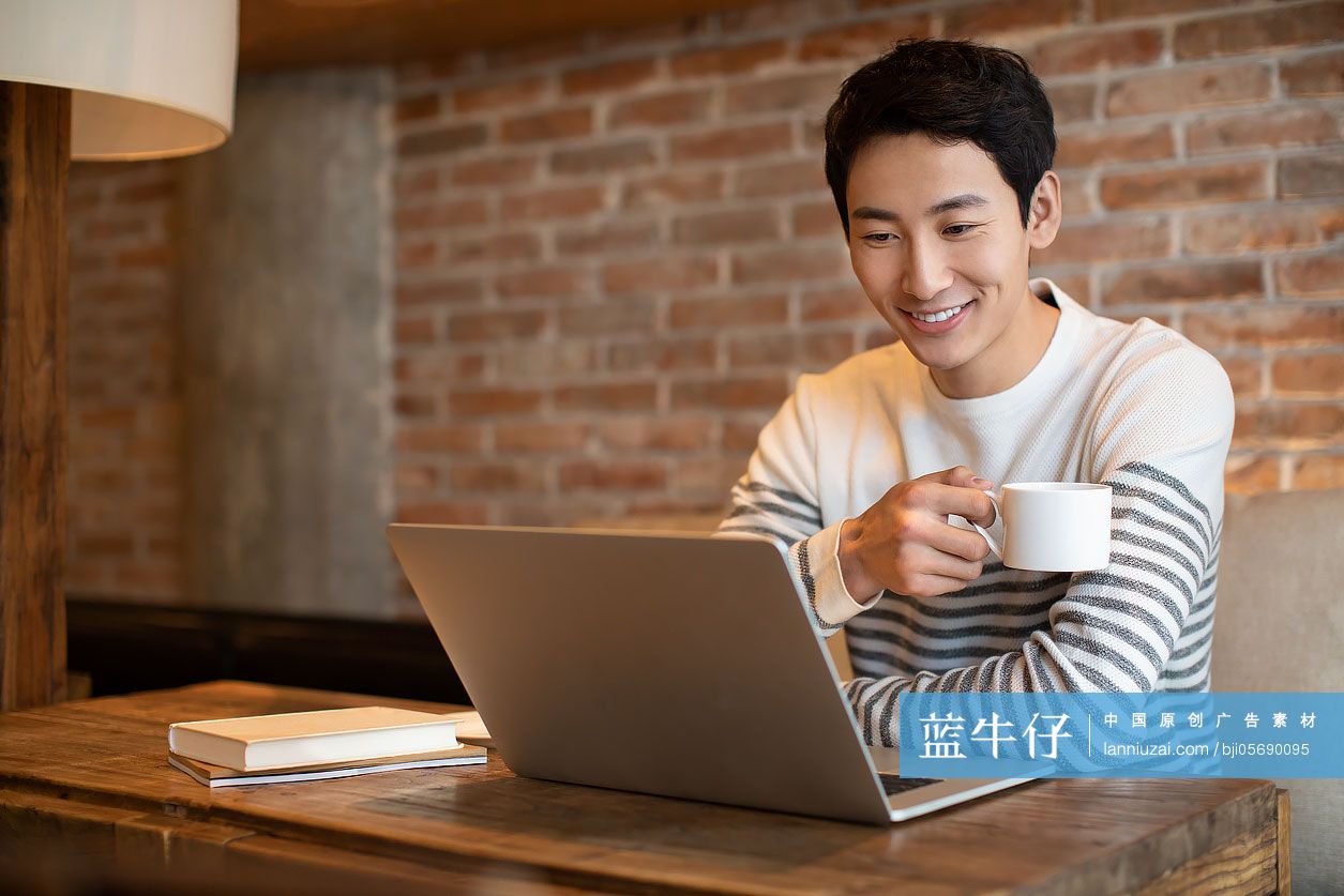 年轻男士在咖啡店使用笔记本电脑
