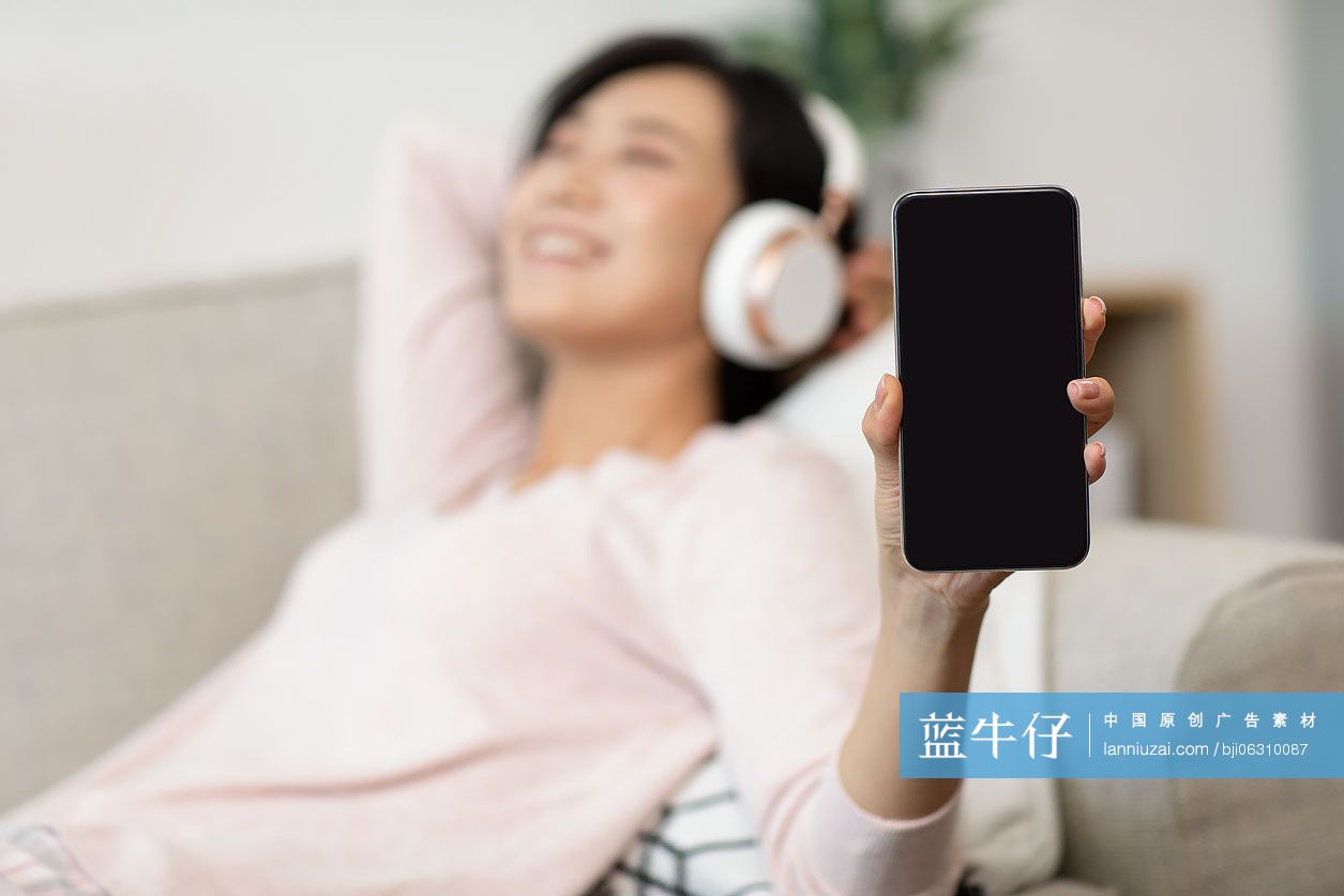 快乐年轻女士在家戴着耳机听音乐