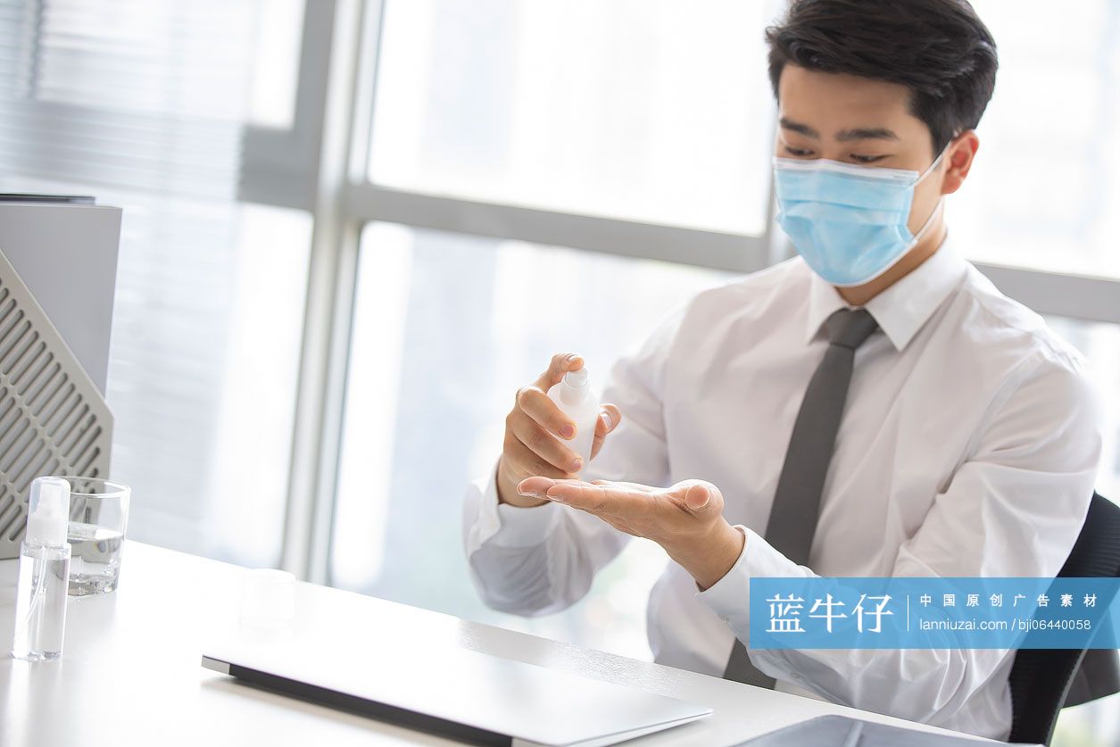 年轻的商务男士在办公室使用免洗洗手液