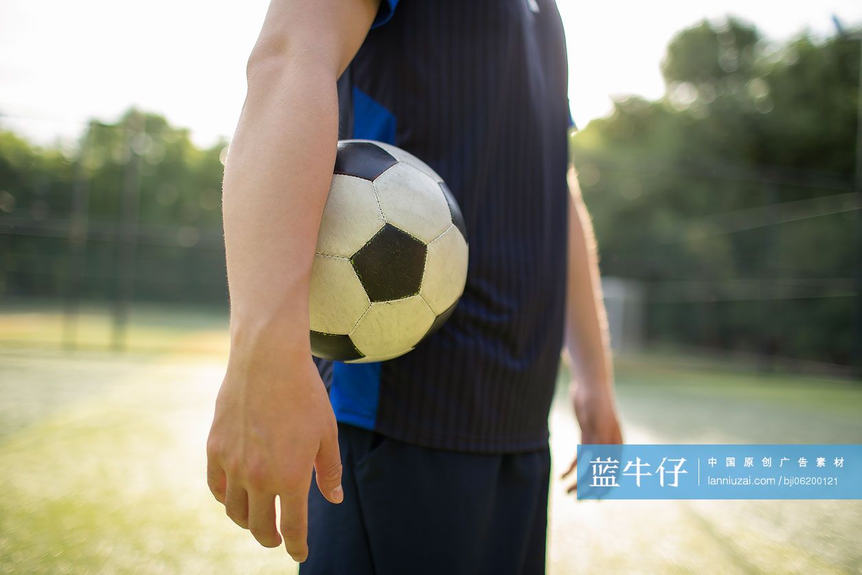 年轻男士在足球场踢足球