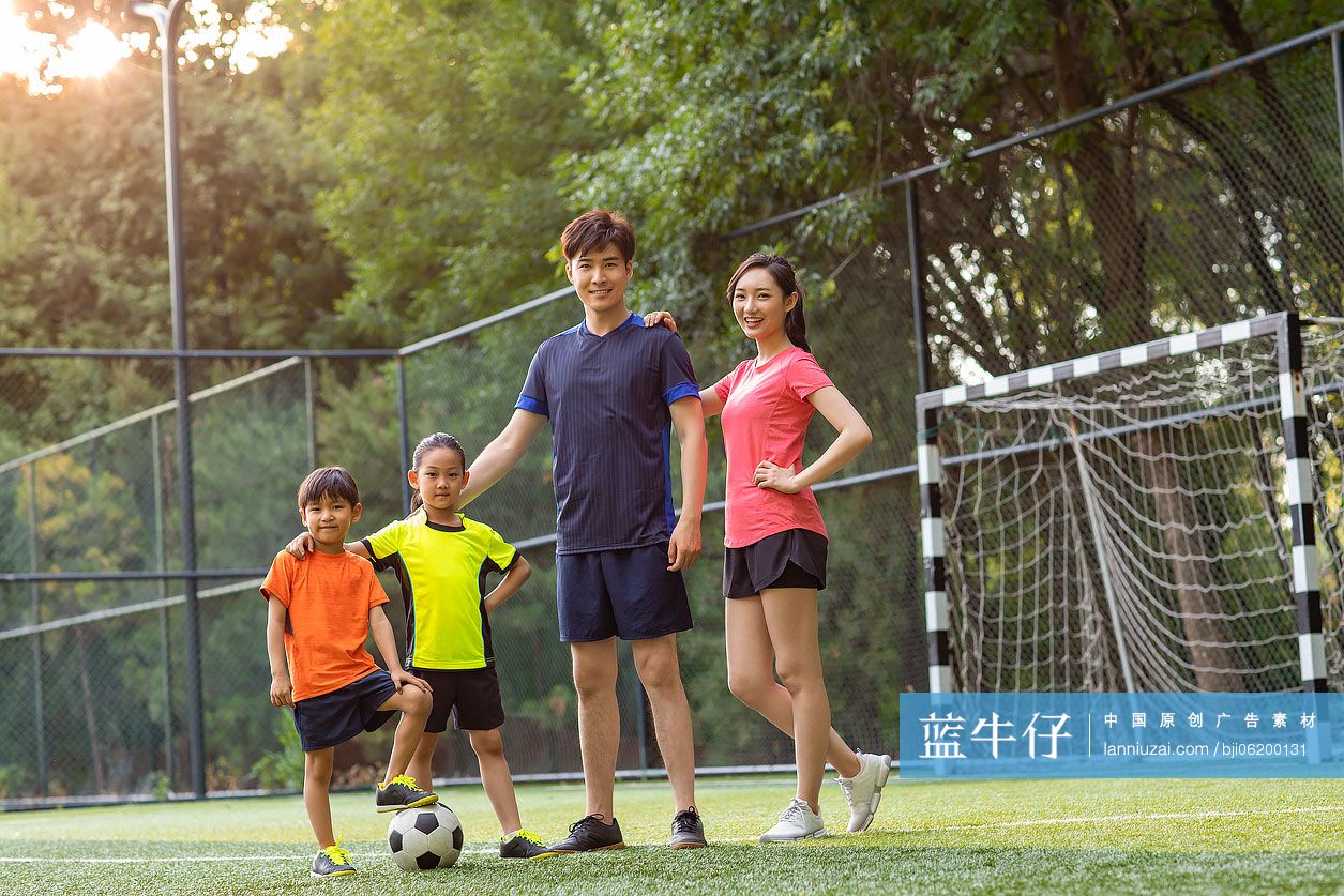 快乐的年轻家庭在足球场踢足球