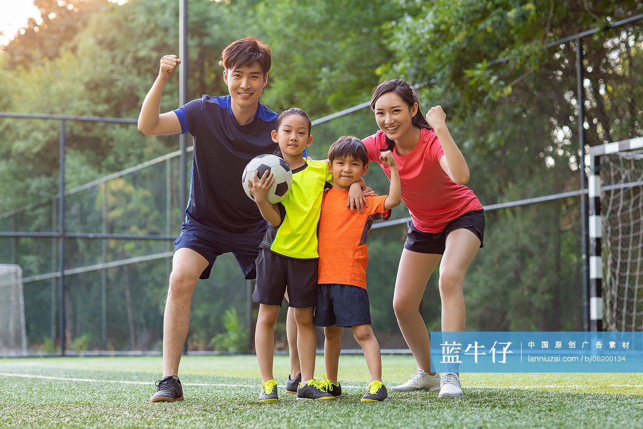 快乐的年轻家庭在足球场踢足球