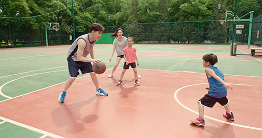 年轻家庭在篮球场打篮球