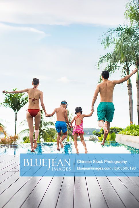 Happy young Chinese family jumping into swimming pool