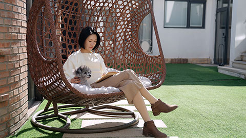 Happy young Chinese woman with pet dog on hanging-chair,4K