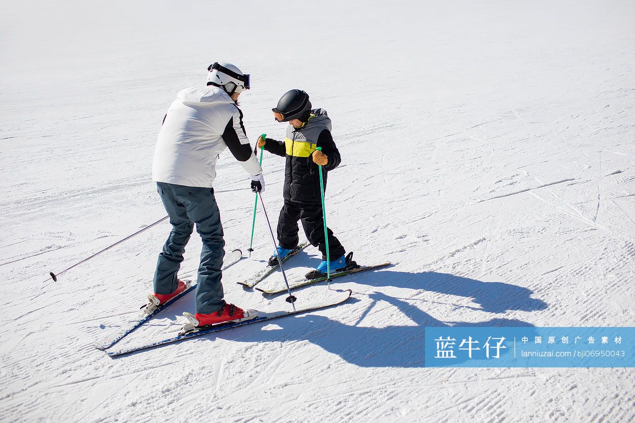 小男孩跟着教练在户外学滑雪