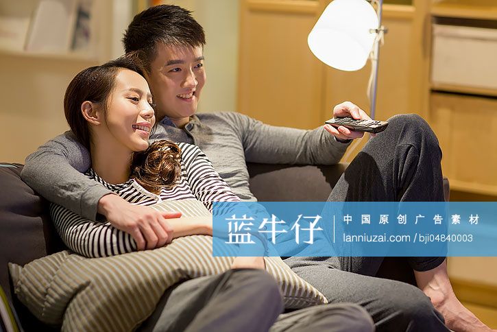 年轻情侣在客厅沙发上看电视