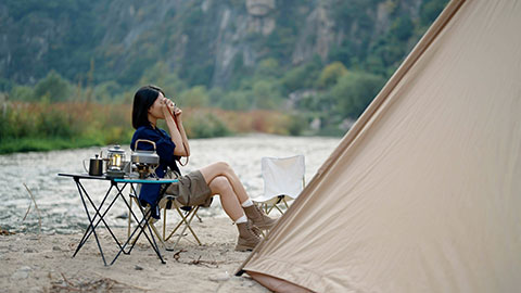 Happy young Chinese woman camping outdoors