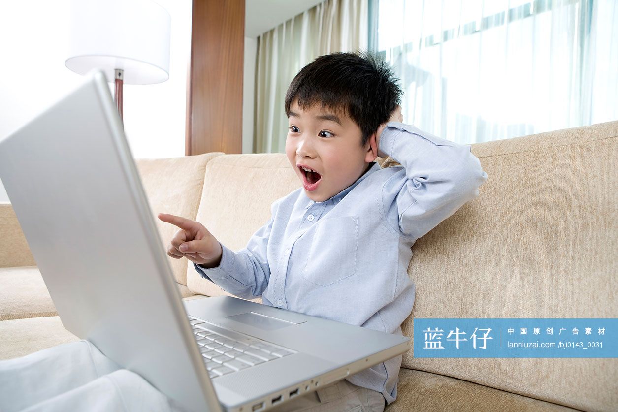 小男孩在沙发上用笔记本电脑上网