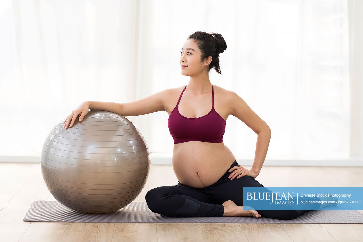Cheerful Chinese pregnant woman with fitness ball