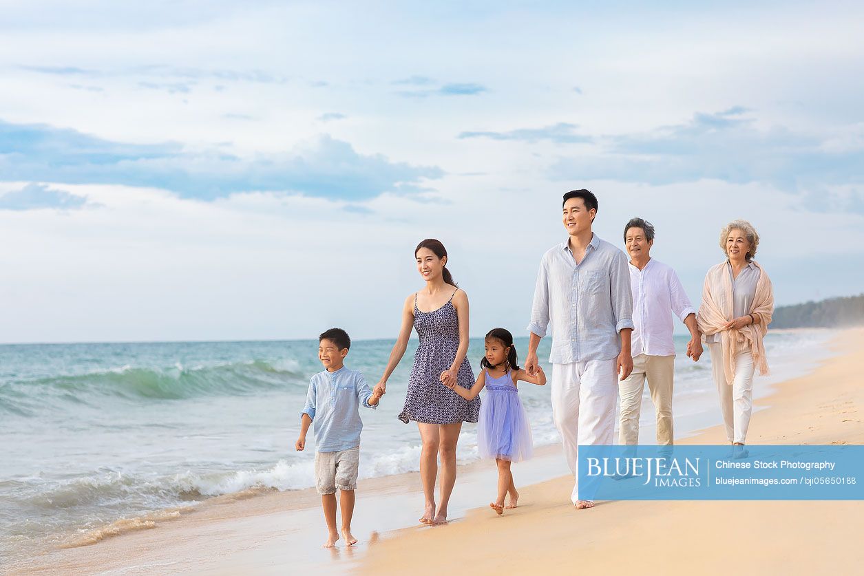 Happy Chinese family walking on beach