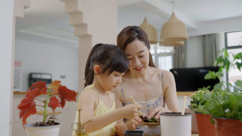 Mum and daughter enjoy potting plants together at home