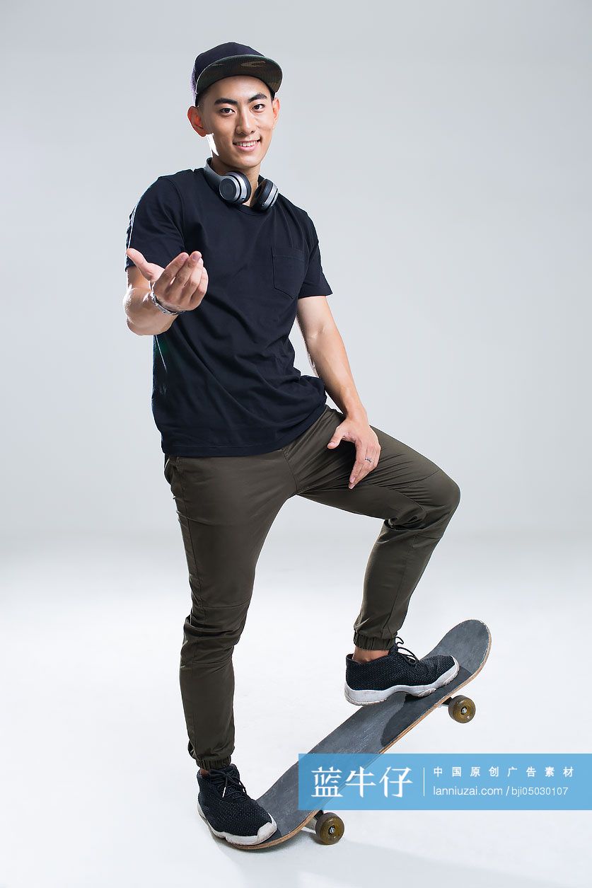 戴耳机的快乐年轻男子在滑滑板