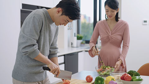 Young pregnant Chinese couple cooking food