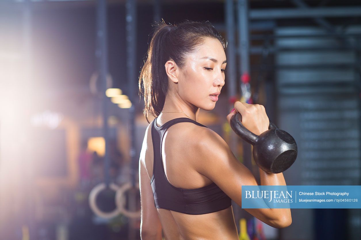 Woman wearing sports bra exercising with a kettle bell Stock Photo