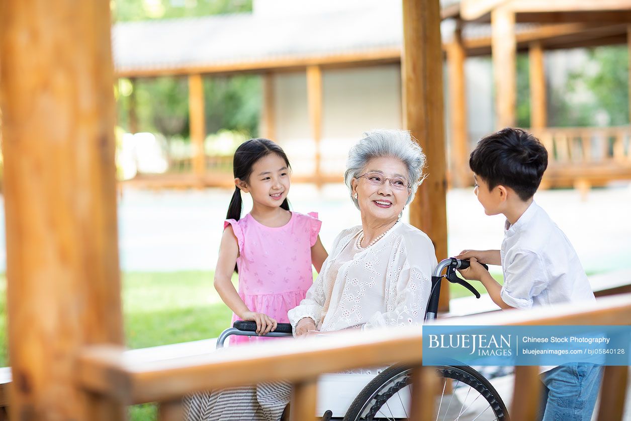 Chinese grandchildren pushing grandmother in wheelchair 
