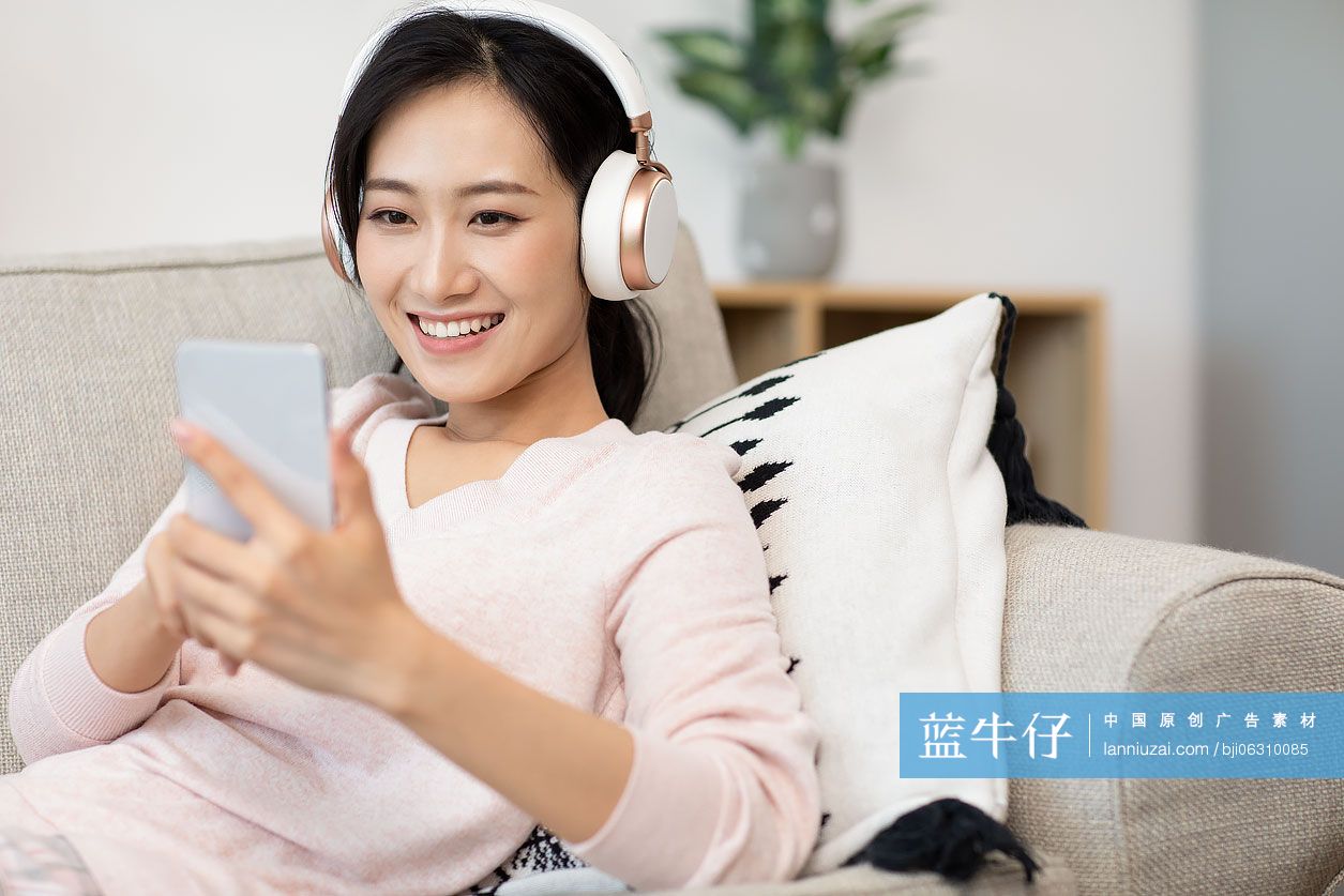 快乐年轻女士在家戴着耳机听音乐