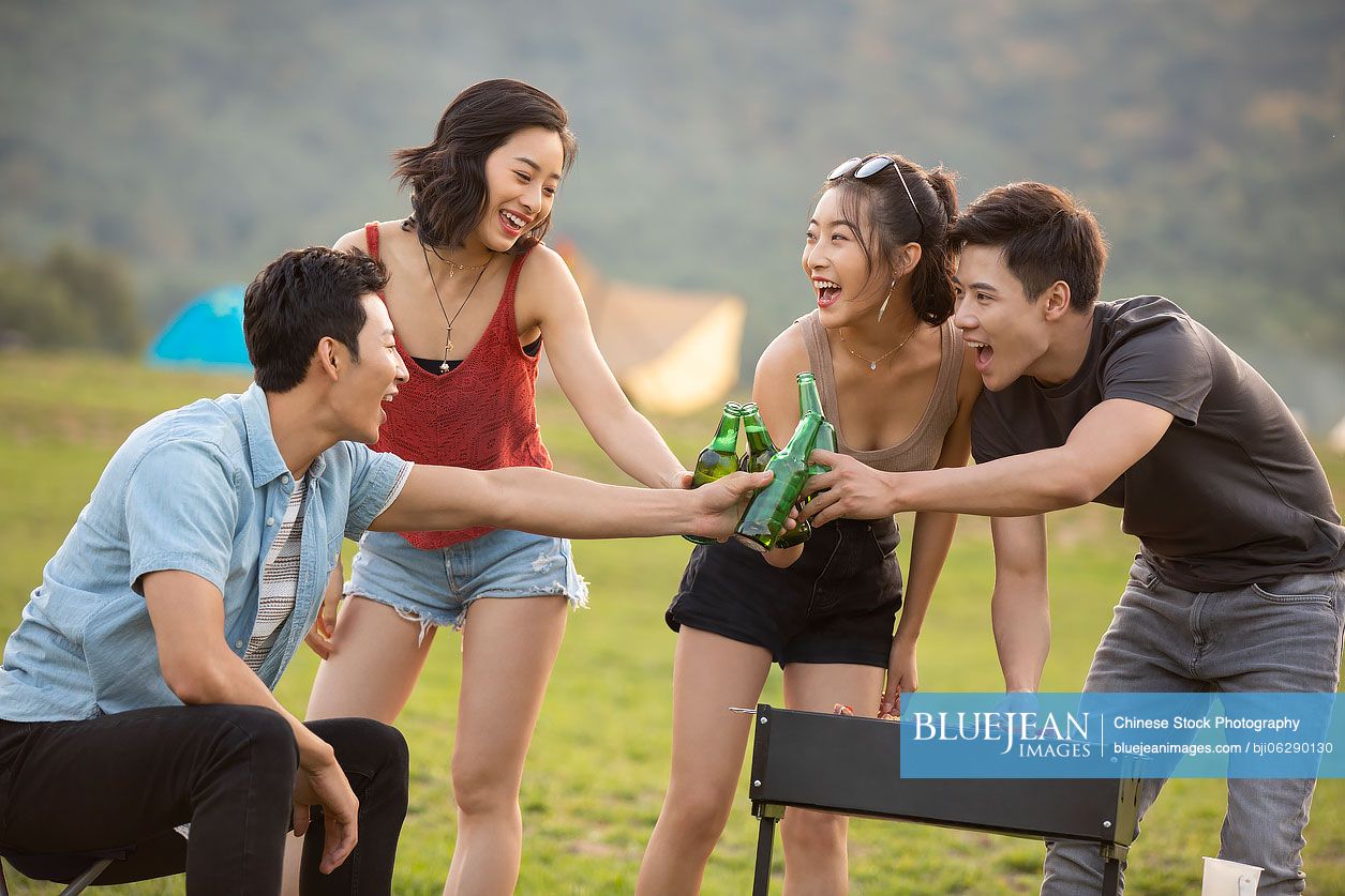 Happy young Chinese friends barbecuing outdoors