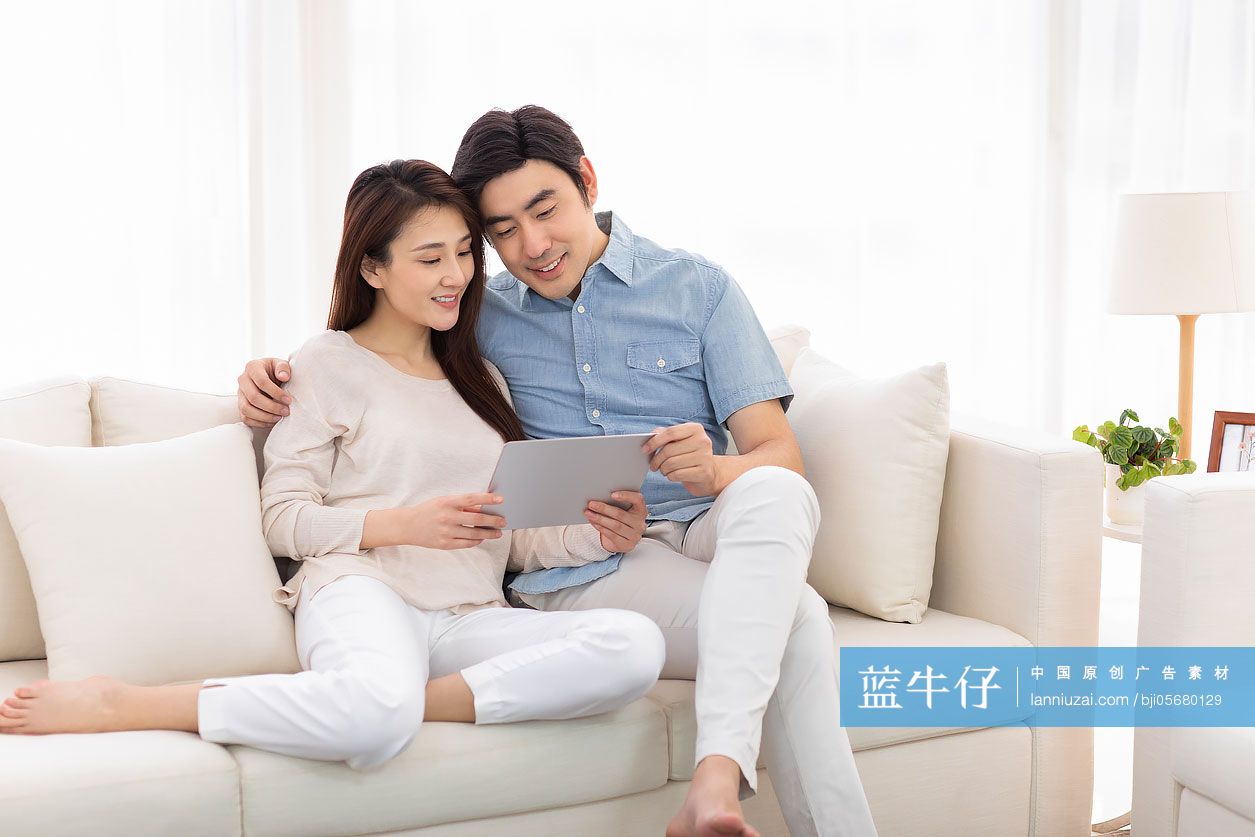 快乐的年轻情侣在客厅使用平板电脑-蓝牛仔影像-中国原创广告影像素材