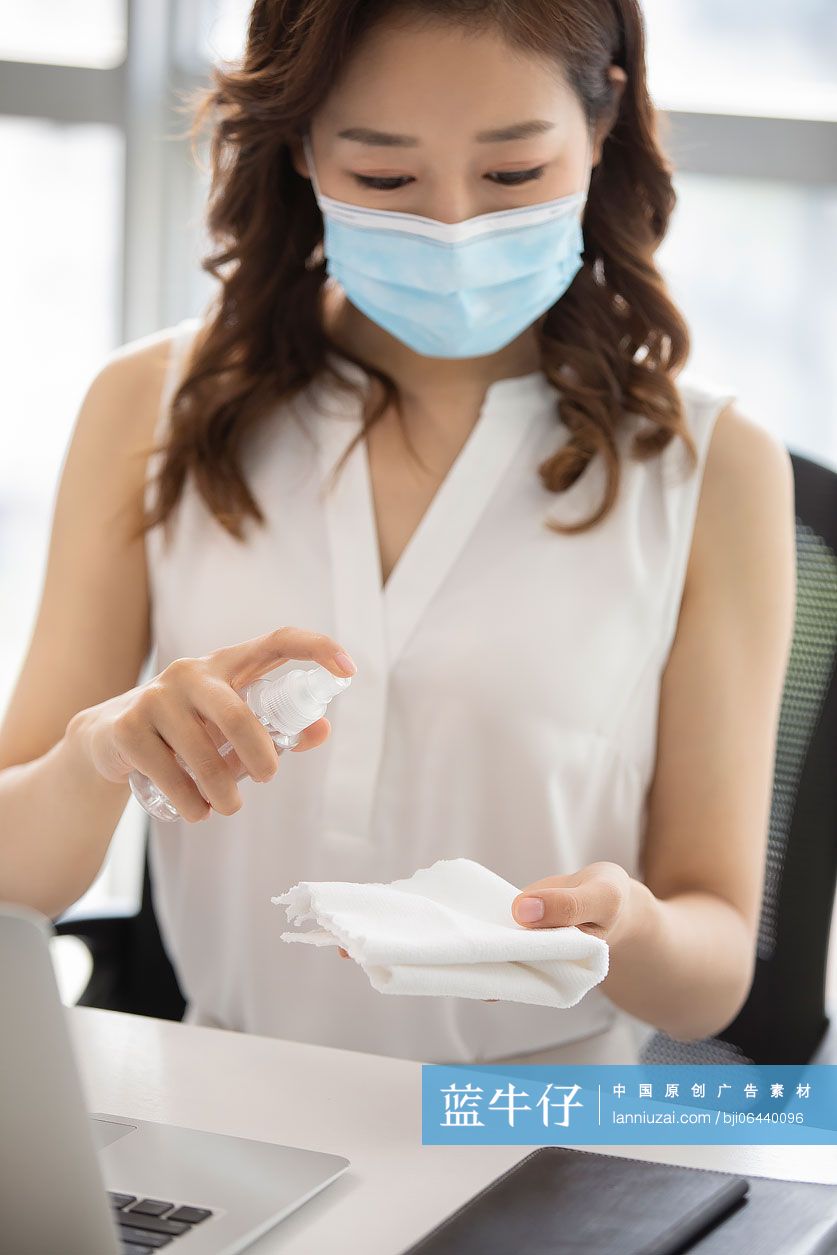 年轻的商务女士在办公室使用消毒液杀菌消毒