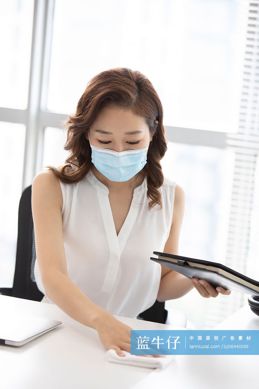 年轻的商务女士在办公室使用消毒液杀菌消毒