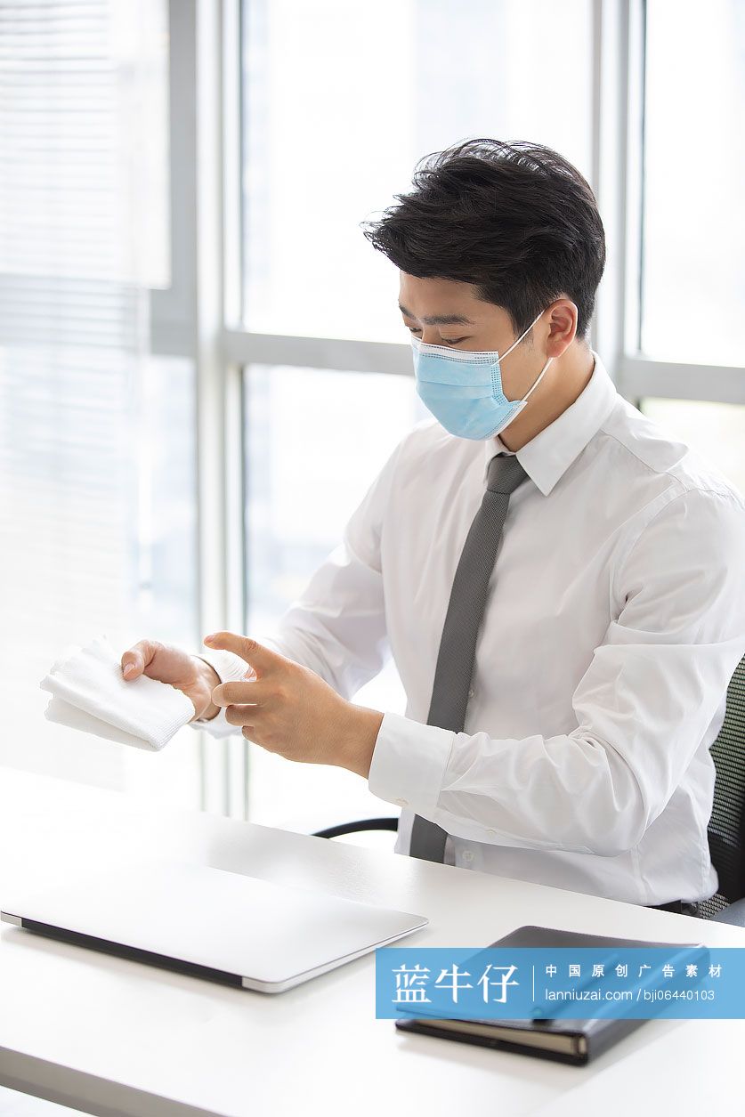 年轻的商务男士在办公室使用消毒液杀菌消毒