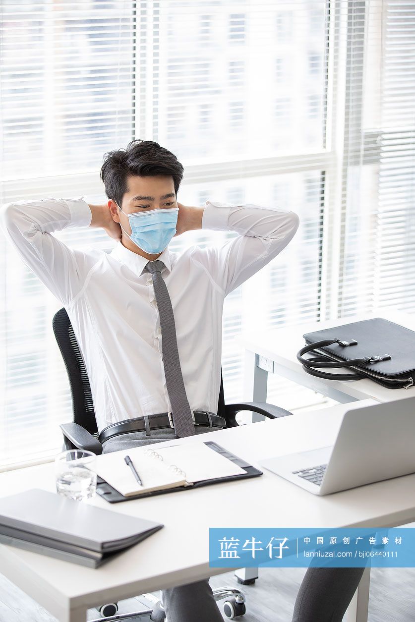 年轻的商务男士戴着口罩工作