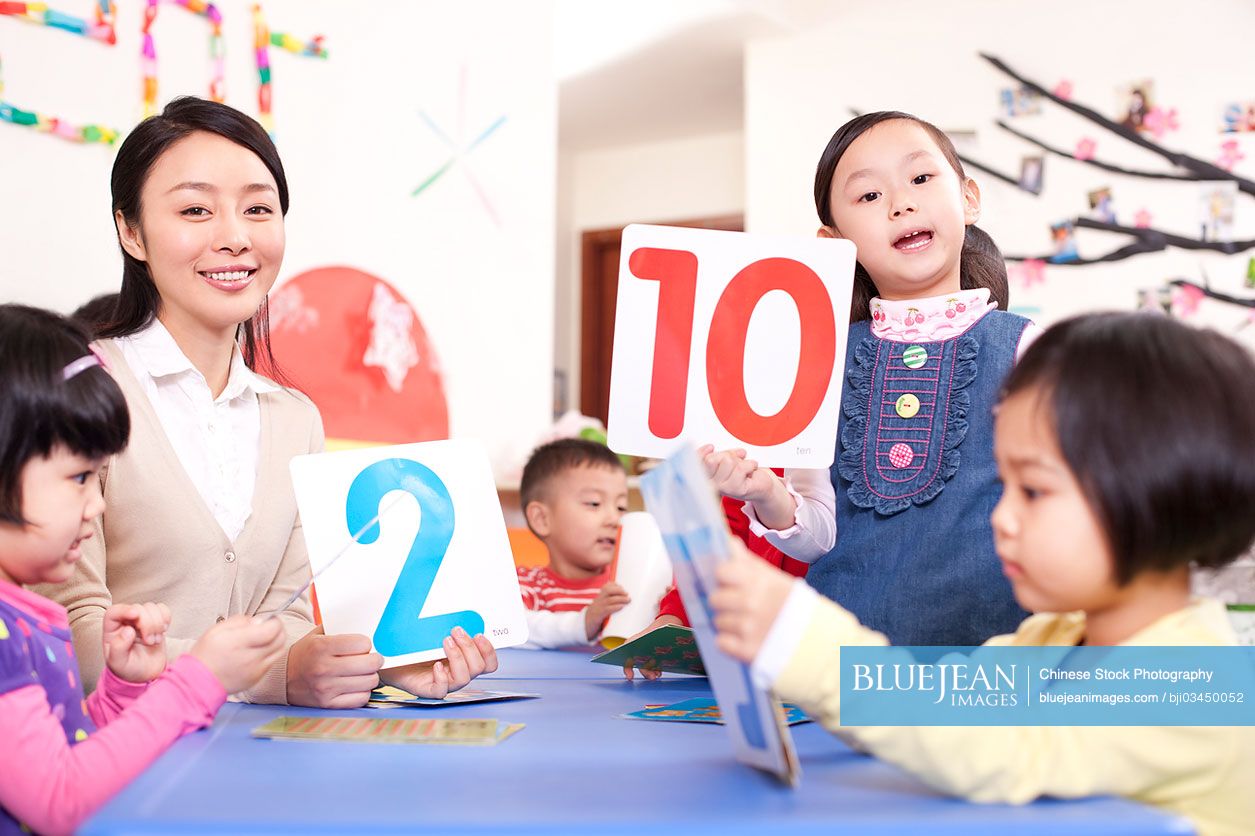 Female Chinese teacher teaching kindergarten children identifying flash cards