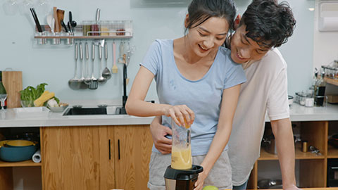 Happy young Chinese couple using juicer in kitchen,4K