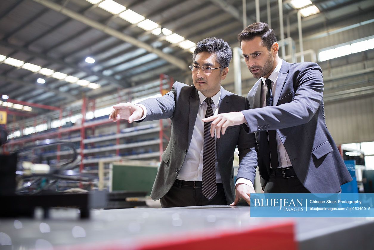 Businessman and engineer checking machine parts in the factory