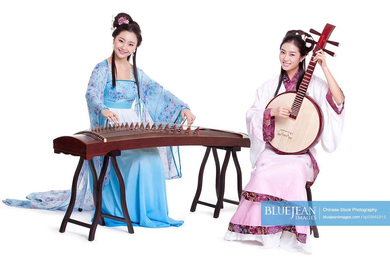 Young Chinese women in Chinese traditional costume plucking classical musical instruments