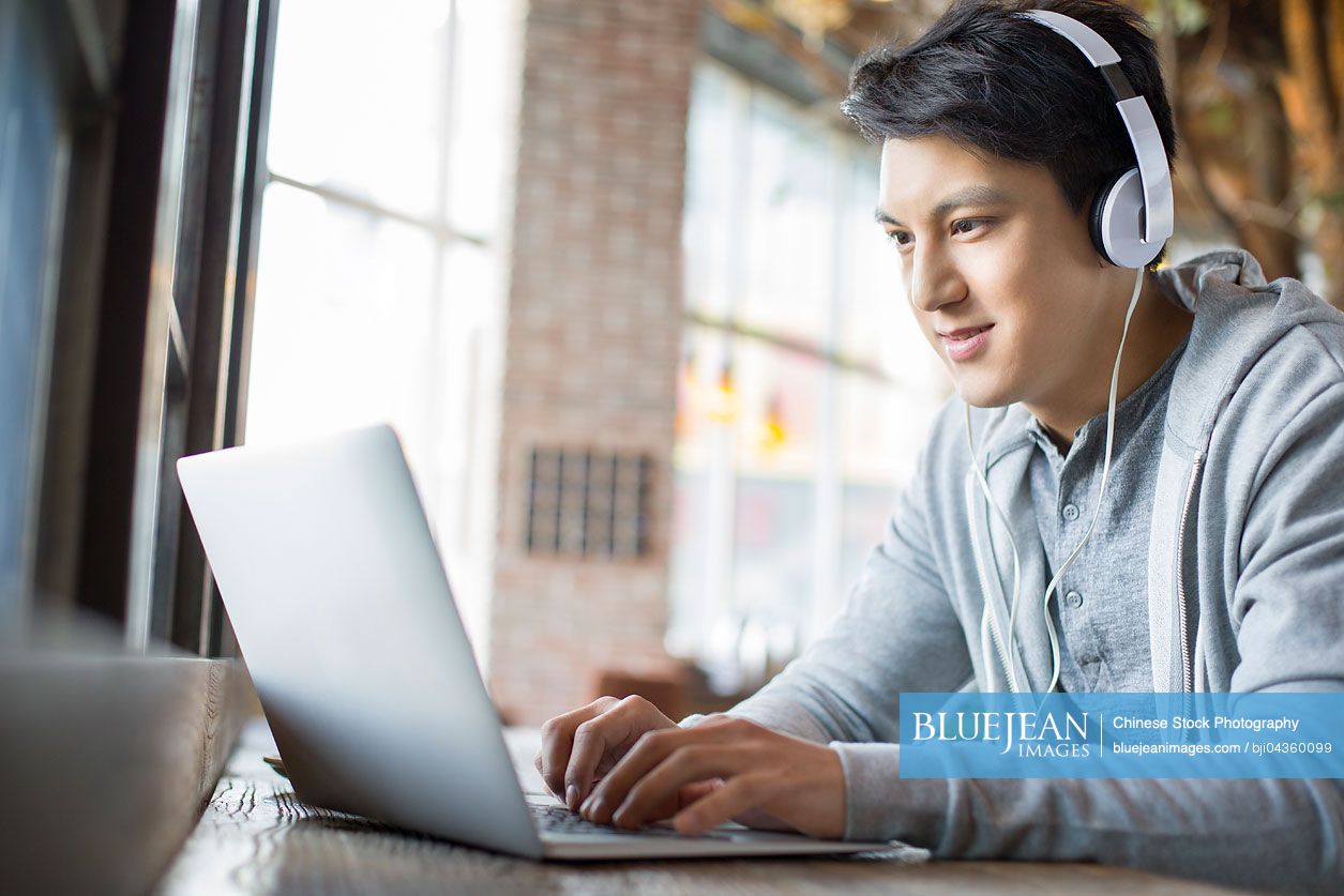 Young Chinese man using laptop in cafe