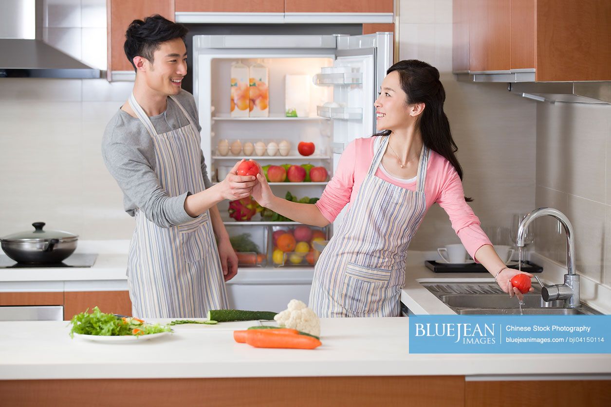 Happy young Chinese couple preparing meal