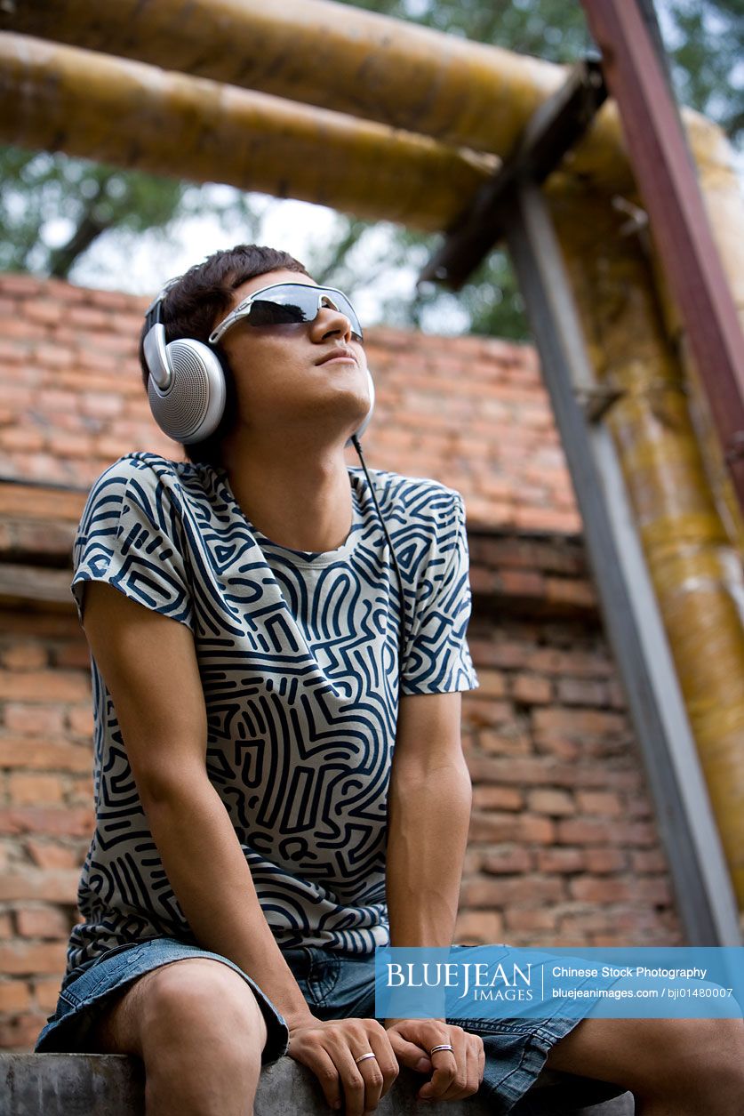 Young Chinese man listening to music on headphones