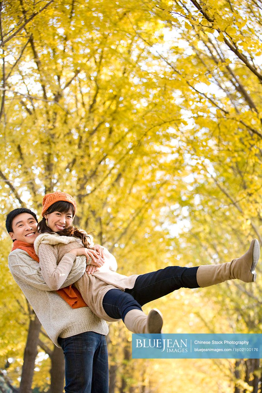 Young Chinese man playfully picking up his girlfriend